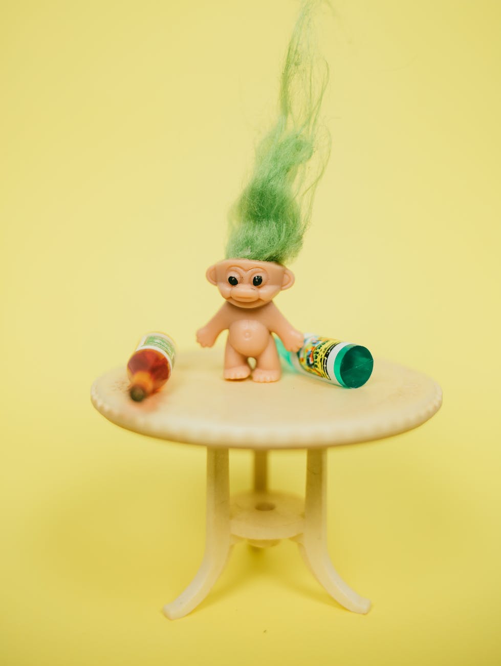 mini troll toy on table with bottles