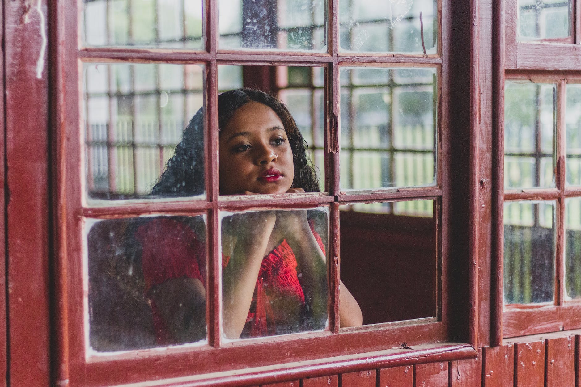thoughtful ethnic woman looking through window